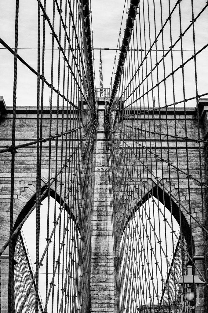 Fine-Art-Fotografie in Schwarz-Weiß: Symmetrische und geometrisch zentrierte Seilkonstruktion der Brooklyn Bridge im minimalistischen Hochkant-Format.