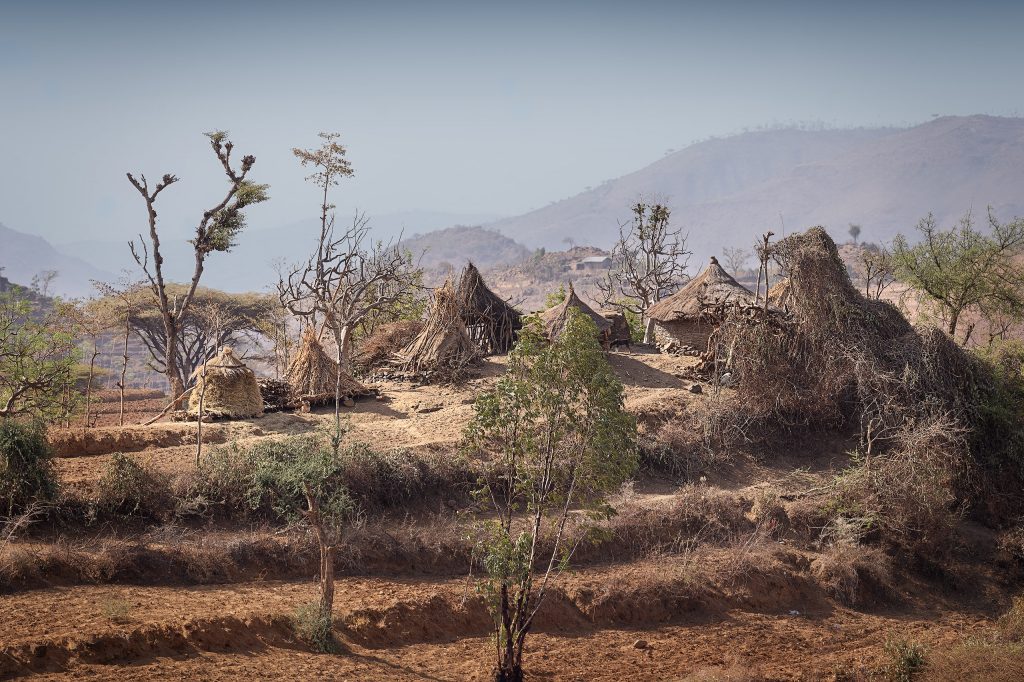 Fine-Art-Fotografie eines Konso-Dorfes in den Bergen: Traditionelle Strohhütten inmitten von charakteristischen Terrassenfeldern, eingebettet in eine typische afrikanische Savannenlandschaft.