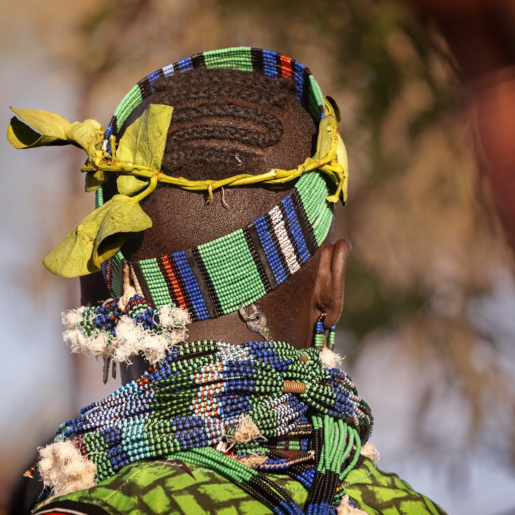 Fine-Art-Fotografie eines Mannes vom Stamm der Hamer von hinten fotografiert; im Fokus steht der üppige, kunstvoll geflochtene Perlenkopfschmuck, der traditionell von den Junggesellen getragen wird.