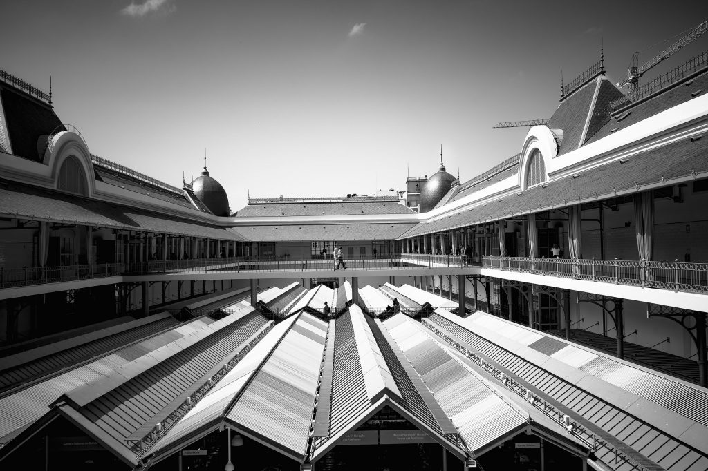 Monochrome Fine-Art-Fotografie aus Porto: Zentrierter Blick auf eine moderne Blechdachkonstruktion in einer Markthalle, eingerahmt von der traditionellen Architektur des historischen Gebäudes.