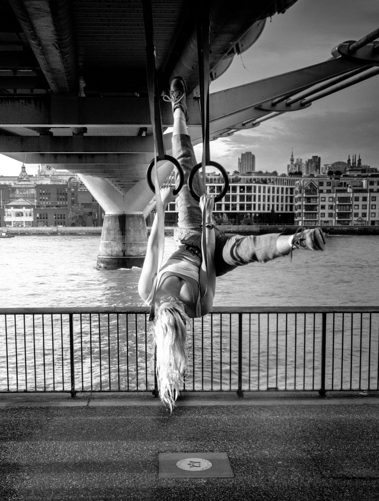 gymnast on rings under the millenium bridge in london