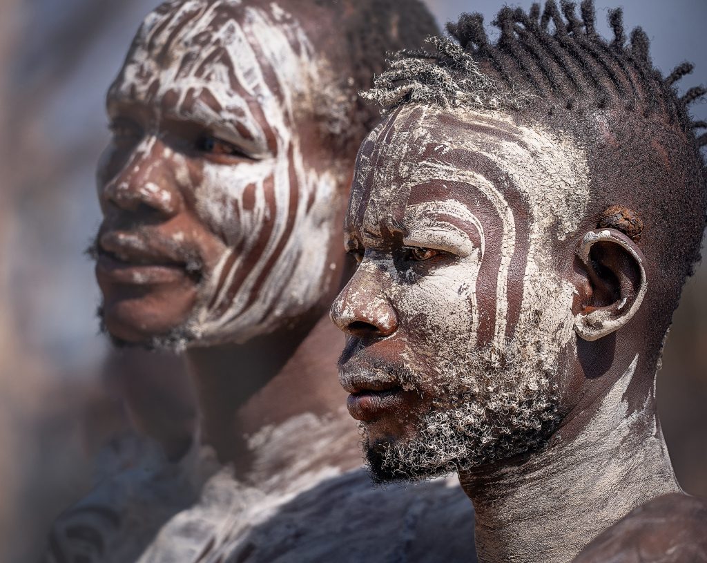 two karo men with pained faces