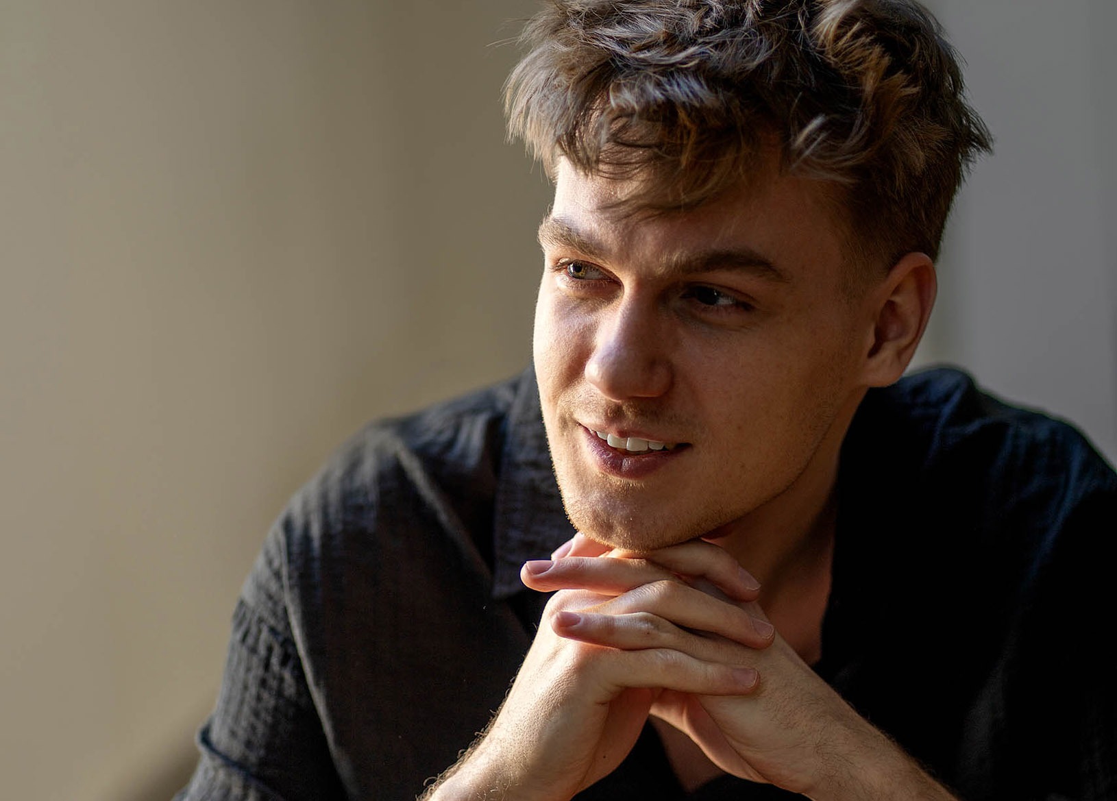 Dramatisches Porträt im Profil: Der Pianist Janick Čhech sitzt im Schneidersitz auf dem Boden, beleuchtet durch intensiven, seitlichen Lichteinfall mit starken Schattenkontrasten.